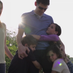 Vater umarmt seine drei Kinder
