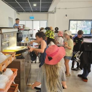 Eine Gruppe Kinder holt sich an der Theke Essen