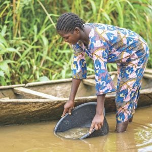 Eine nigerianische Frau schöpft Wasser aus einem verunreinigten Fluss
