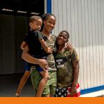 Mutter mit zwei Kindern vor ihrem neuen Haus auf Jamaika